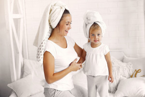 Beautiful woman with child. Woman in a white towel. Little daughter in a bedroom